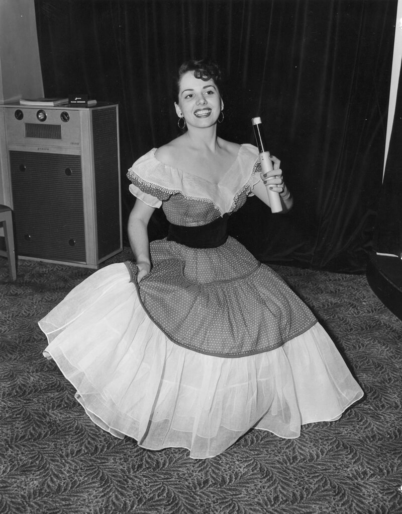 Moça segurando microfone sem fio na década de 50